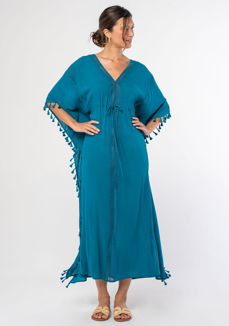 [Color: Teal] A woman wearing a sheer teal bohemian beach cover up maxi dress with lace and tassel trim and side slits. A kimono kaftan maxi dress perfect for vacations! 