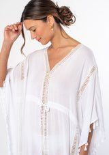 [Color: White] A woman wearing a sheer white bohemian beach cover up maxi dress with lace and tassel trim and side slits. A kimono kaftan maxi dress perfect for vacations! 