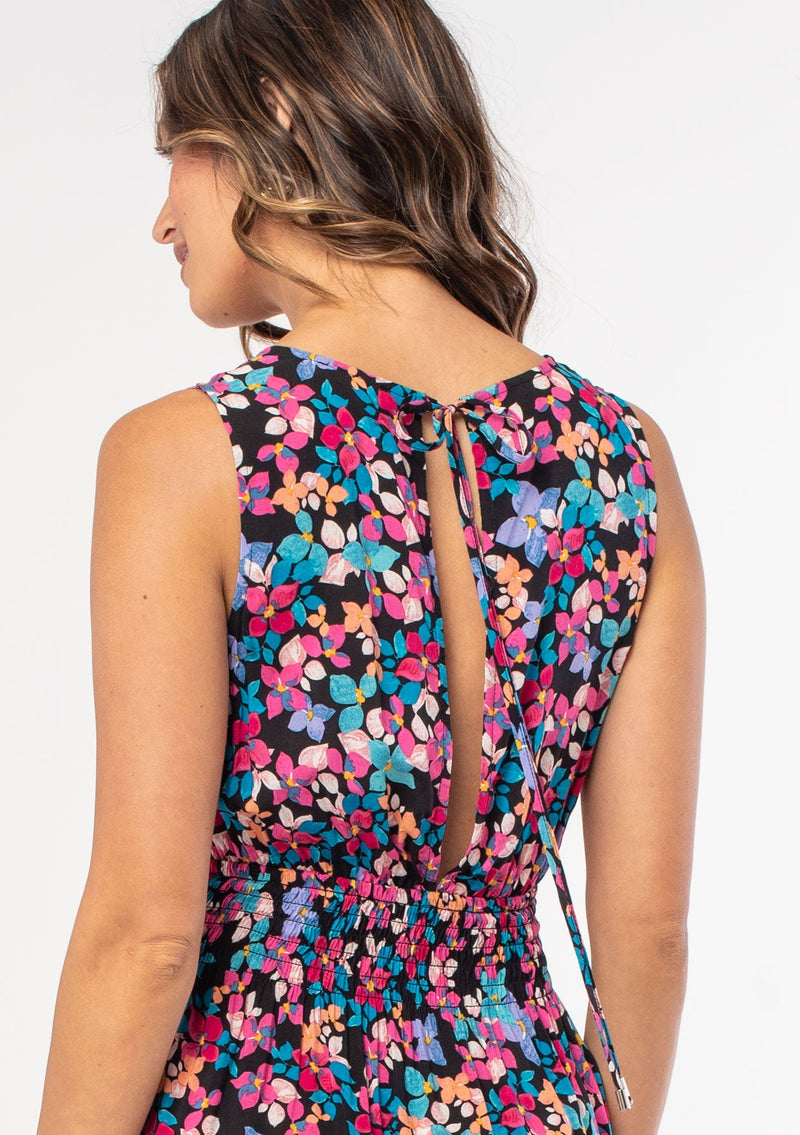 [Color: Black/Fuchsia] A woman wearing a casual sleeveless bohemian mini dress in a black and pink floral print. 