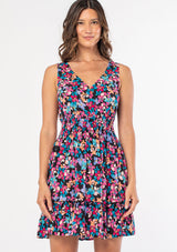 [Color: Black/Fuchsia] A woman wearing a casual sleeveless bohemian mini dress in a black and pink floral print. 