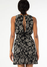 [Color: Black/Natural] A back facing image of a black model wearing a sleeveless bohemian mini dress in a black and natural floral print. A chiffon tank dress with a smocked elastic waist and an open back with a tassel tie closure. 