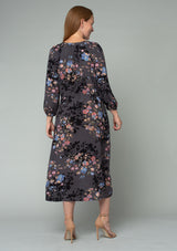 [Color: Grey/Dusty Blue] A back facing image of a red headed model wearing a lightweight bohemian mid length dress in a grey and blue floral print. With three quarter length sleeves, a button front, side pockets, and an adjustable drawstring waist. 
