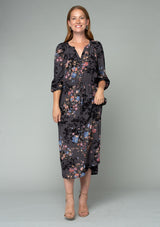 [Color: Grey/Dusty Blue] A full body front facing image of a red headed model wearing a lightweight bohemian mid length dress in a grey and blue floral print. With three quarter length sleeves, a button front, side pockets, and an adjustable drawstring waist. 