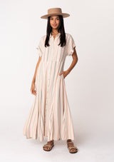 [Color: Natural/Sage] A front facing image of a brunette model wearing a bohemian flowy maxi shirt dress in a natural and sage green stripe. With short cuffed sleeves, a button front, a collared neckline, side pockets, a paneled skirt, and a back waist tie.