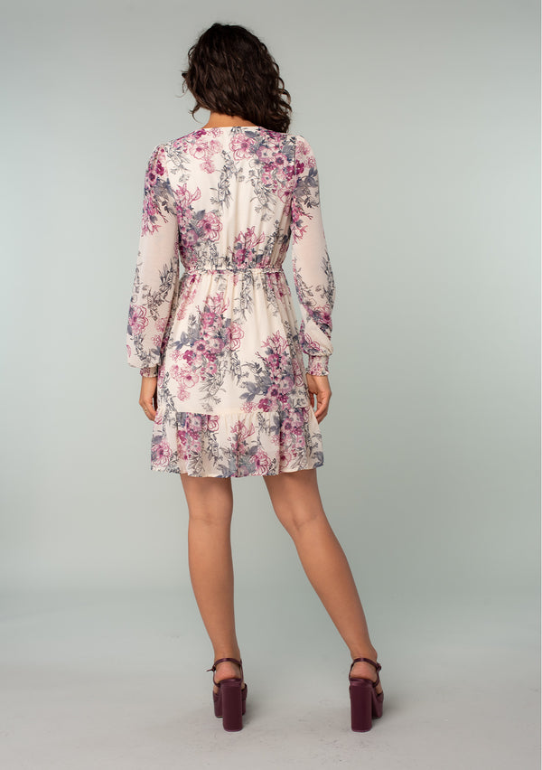 [Color: Natural/Wine] A back facing image of a brunette model wearing a sheer chiffon bohemian mini dress in a natural and wine pink floral print. With long sleeves, a button front top, ruffle details, and a tiered skirt. 