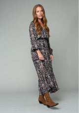 [Color: Black/Rose] A side facing image of a red headed model wearing a classic bohemian maxi dress in a black and pink paisley print. With long sleeves, side slits, and an elastic waist. 