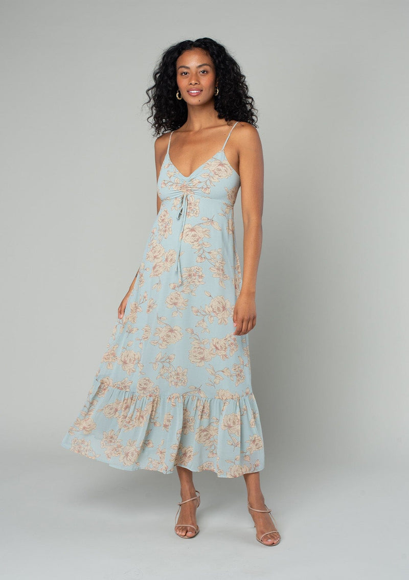 [Color: Dusty Blue/Natural] A front facing image of a brunette model wearing a pretty chiffon mid length slip dress in a dusty blue and natural floral print. With adjustable spaghetti straps, a flowy tiered skirt, a half smocked elastic waist at the back, an empire waist, and a gathered top with drawstring. 