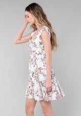 [Color: Mint/Rose] A side facing image of a blonde model wearing a spring bohemian mini dress in a mixed pink floral print. With short cap sleeves, a square neckline, an empire waist, a paneled skirt, and a back tie closure. 