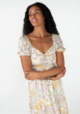 [Color: Natural/Pink] A close up front facing image of a brunette model wearing a bohemian spring maxi dress in an ivory, pink, and yellow vintage inspired floral print. With a sweetheart neckline, short puff sleeves, an empire waist, a flowy tiered skirt, and a smocked elastic bodice at the back. Designed in a pretty textured swiss dot. 