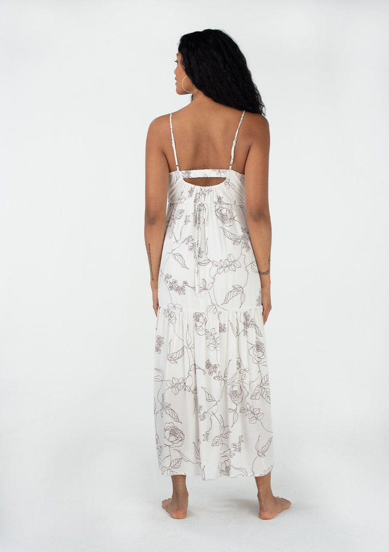 [Color: Natural/Taupe] A back facing image of a brunette model wearing a sleeveless spring maxi dress in an ivory and taupe floral print. With adjustable spaghetti straps, a scoop neckline, a flowy tiered skirt, a back cutout detail, and a drawstring waist tie at the back. If you're going for the coastal cowgirl trend, this dress was made for you! Pair this flattering white maxi dress with cowboy boots and a cowgirl hat for an ultra bohemian and modern outfit.