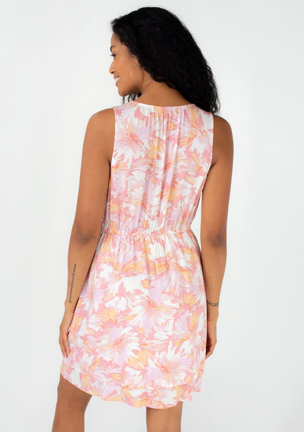 [Color: Peach/Light Pink] A back facing image of a brunette model wearing a pretty sleeveless spring mini dress in a pink floral print. With a surplice v neckline, an elastic waist, and a double layered tiered skirt. 