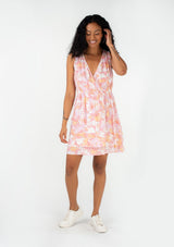 [Color: Peach/Light Pink] A full body front facing image of a brunette model wearing a pretty sleeveless spring mini dress in a pink floral print. With a surplice v neckline, an elastic waist, and a double layered tiered skirt. 