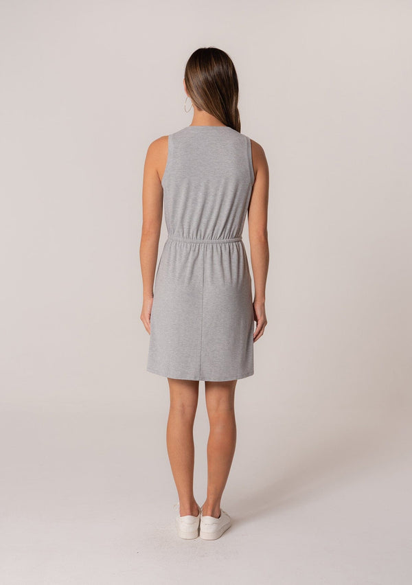 [Color: Heather Grey] A back facing image of a brunette model wearing a sporty sleeveless lounge mini dress in heather grey. Designed in a soft bamboo knit with a scoop neckline, side pockets, and an adjustable drawstring waist. 