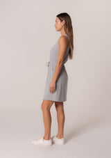 [Color: Heather Grey] A side facing image of a brunette model wearing a sporty sleeveless lounge mini dress in heather grey. Designed in a soft bamboo knit with a scoop neckline, side pockets, and an adjustable drawstring waist. 