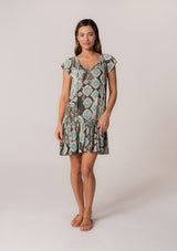 [Color: Black/Aqua] A front facing image of a brunette model wearing a lightweight summer mini dress in a green bohemian print. With short flutter sleeves, a split v-neckline with ties, and a ruffle trimmed tiered skirt. 