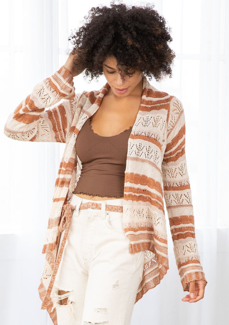 [Color: Cream/Rust] A model wearing a cream and rust striped rochet cardigan. A vintage inspired style with a waterfall hemline and a removable waist tie. 