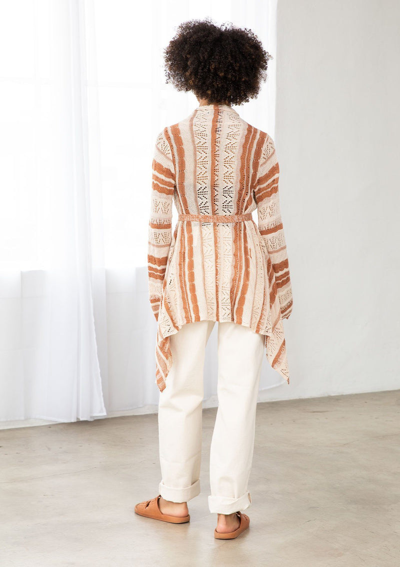 [Color: Cream/Rust] A model wearing a cream and rust striped rochet cardigan. A vintage inspired style with a waterfall hemline and a removable waist tie. 