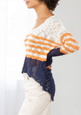 [Color: Ivory/Orange] A model wearing an ivory and orange striped color block lightweight bohemian beach sweater. With an open tie back detail, long sleeves, a dropped shoulder, and a high low hemline.