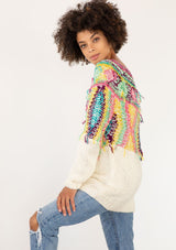 [Color: Ivory/Multi] A model wearing an ivory sweater with bohemian multicolor shaggy yarn yoke detail. With a wide scoop neckline, long sleeves, and a long length. 
