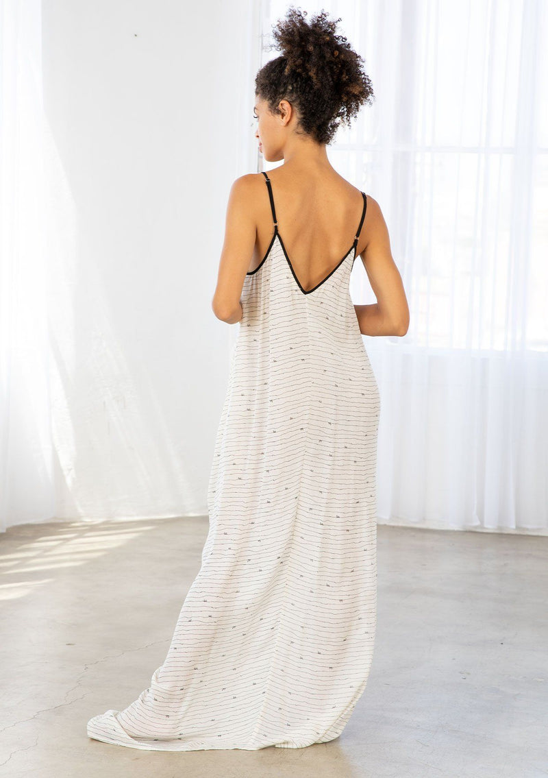 [Color: Black/Natural] A model wearing an off white maxi dress with black snail print design. Featuring a v neckline, adjustable spaghetti straps, and side pockets.