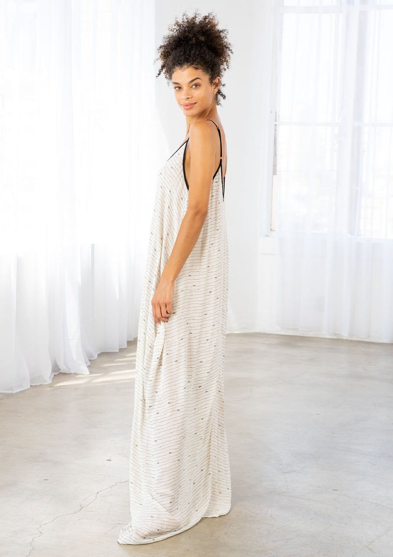 [Color: Black/Natural] A model wearing an off white maxi dress with black snail print design. Featuring a v neckline, adjustable spaghetti straps, and side pockets.