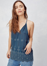 [Color: Dusty Navy] An image of a blonde model wearing a navy boho embroidered tank top with tassel ties. 