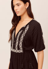 [Color: Black/Taupe] A blond and brunette woman wearing adorable embroidered bohemian mini dress. Featuring a tassel tie cinched waist and split neckline with elbow length sleeves. 