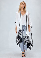 [Color: Black/White] Blonde model wearing a white bohemian kimono cover up with black border and unique black floral print. Styled over a white camisole tank top, lightwash denim jeans and black strappy sandals