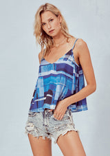 [Color: Blue] A blonde model wearing an abstract blue tank top with a flowy fit, v-neckline, and adjustable spaghetti straps. 