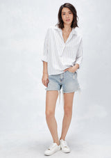 [Color: Natural/Red/Blue] A front facing image of a brunette model wearing a yarn dyed stripe shirt with subtle red stripe accents. Featuring a classic collar neckline, 3/4 length rolled sleeves, and a high low hemline. A relaxed and cool shirt for the warmer weather. 