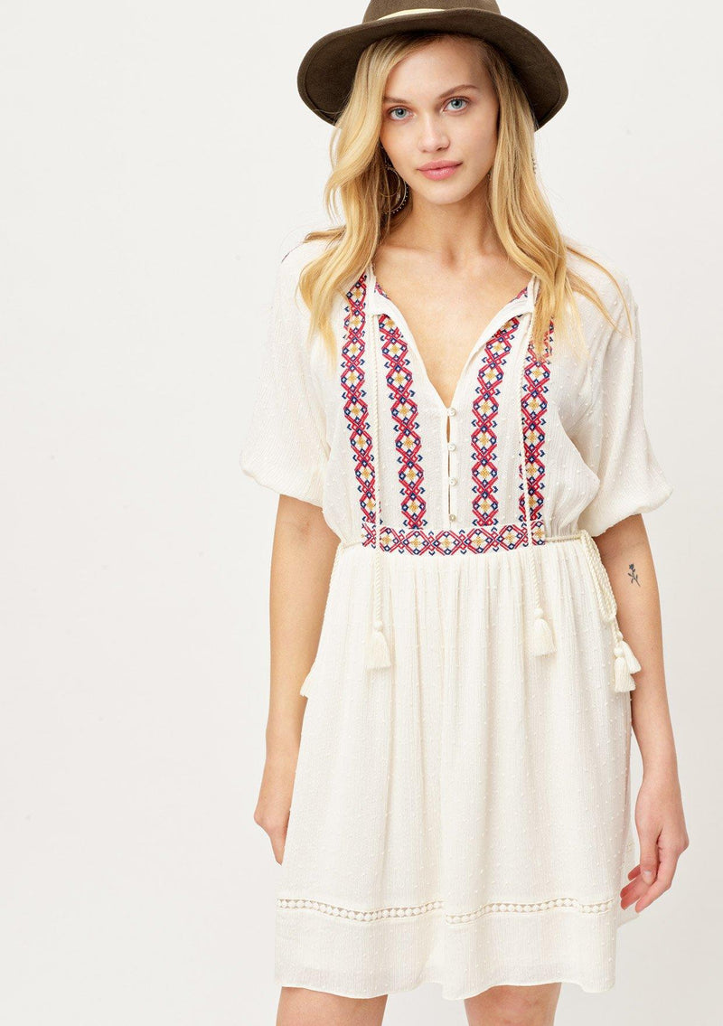 [Color: OffWhite/Multi] A blond woman wearing adorable embroidered bohemian mini dress. Featuring a tassel tie cinched waist and split neckline with elbow length sleeves. 