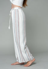 [Color: Ivory/Red] A half body side facing image of a model wearing an off white and red striped wide leg drawstring pant.