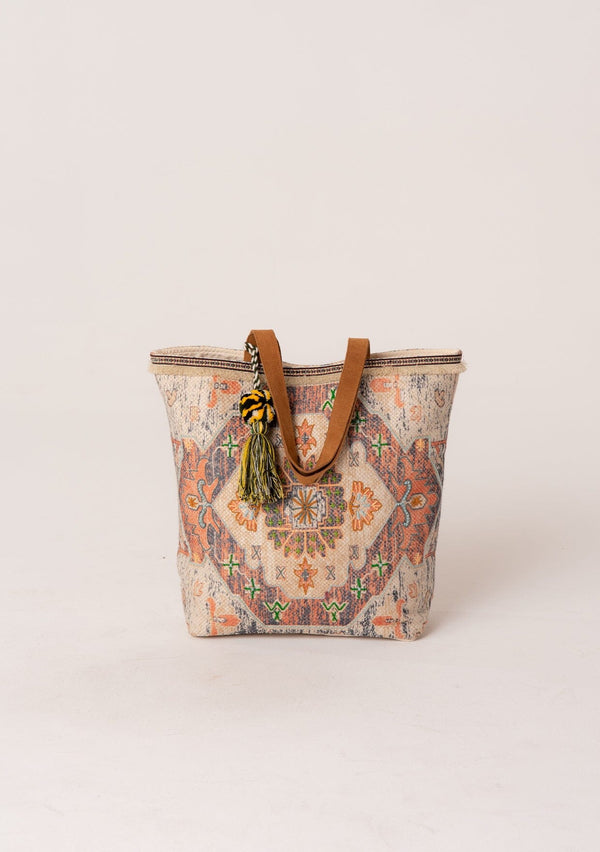 [Color: Natural/Cognac] A bohemian tote bag with tapestry design, an oversize pom tassel accent, two straps, and a magnetic closure. 