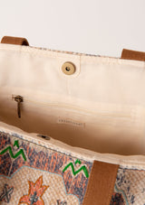[Color: Natural/Cognac] An image of the inside of a bohemian tote bag with tapestry design, an oversize pom tassel accent, two straps, and a magnetic closure. 