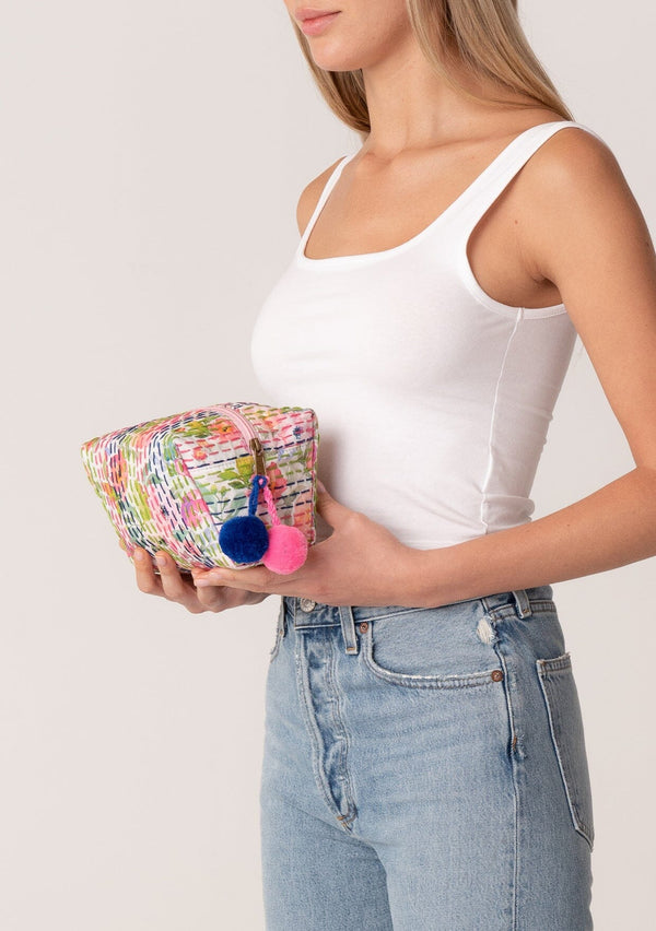 [Color: Off White/Pink] A bohemian small makeup travel bag in a pink and green floral print. With a zip closure, pom accent, and stitch details throughout. 