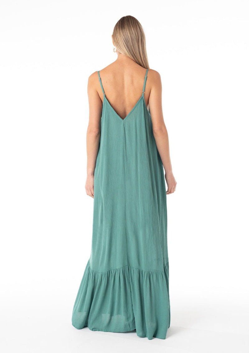 [Color: Seaglass Green] A back facing image of a blonde model wearing a simple flowy sleeveless maxi tank dress in a teal crinkle rayon. With a v neckline in front and back, adjustable spaghetti straps, and a tiered skirt. 