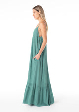 [Color: Seaglass Green] A side facing image of a blonde model wearing a simple flowy sleeveless maxi tank dress in a teal crinkle rayon. With a v neckline in front and back, adjustable spaghetti straps, and a tiered skirt. 