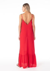 [Color: Tomato] A back facing image of a blonde model wearing a simple flowy sleeveless maxi tank dress in a bright red crinkle rayon. With a v neckline in front and back, adjustable spaghetti straps, and a tiered skirt. 