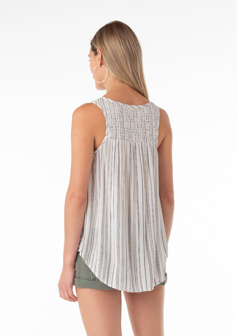 [Color: Off White/Black] An angled back facing image of a blonde model wearing a casual bohemian spring tank top in an off white and black stripe. With a v neckline, a smocked yoke detail, and a relaxed fit. 