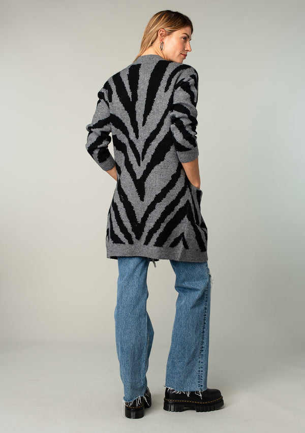 [Color: Charcoal/Black] A model wearing a charcoal and black tiger print cardigan. Featuring a mid length, long sleeves, side pockets, and an open front.