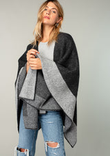 [Color: Heather Charcoal/Heather Cement] A front facing image of a blonde model wearing a soft and warm mid length sweater cape. An open front cape cardigan with a contrast border design. Perfect fall sweater, great for layering. 