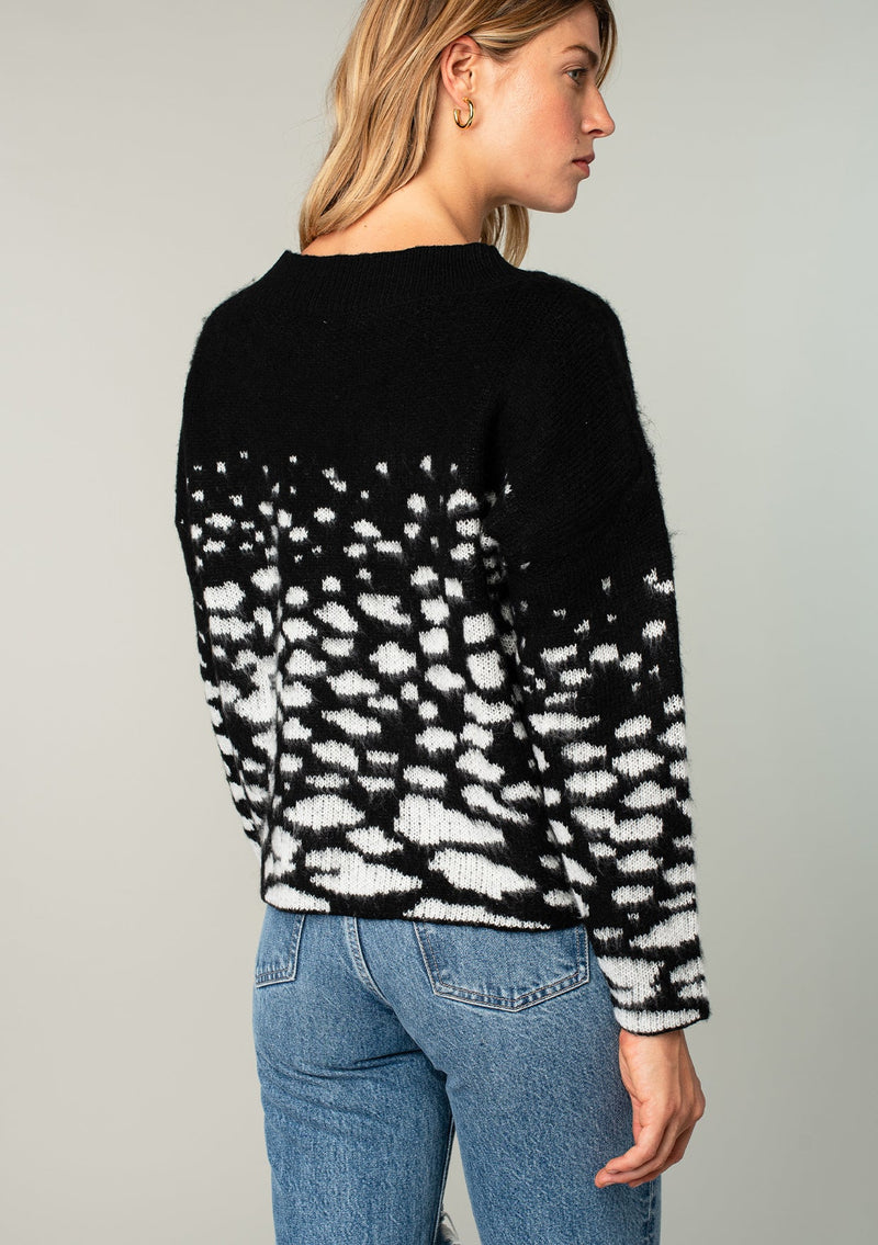 [Color: Black/Ivory] A model wearing a fuzzy black sweater in an abstract animal print. With a slightly cropped length, long sleeves, and a round neckline.