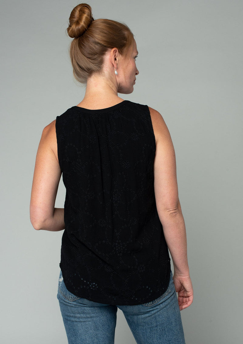 [Color: Black] A back facing image of a red headed model wearing a black eyelet bohemian tank top. With a split v neckline and tassel ties.