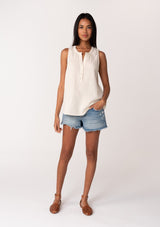 [Color: Cloud] A full body front facing image of a brunette model wearing a simple cotton off white tank top with a button front, a v neckline, and a relaxed fit. 