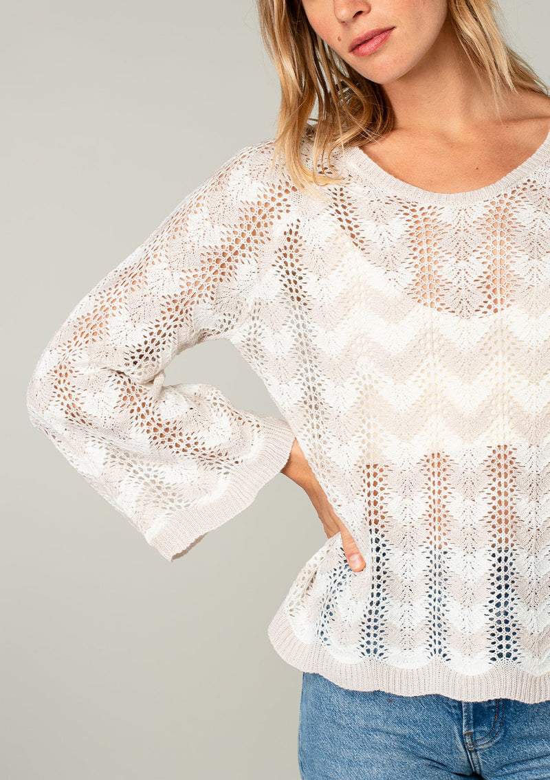 [Color: Linen/Ivory] A model wearing a beige and off white crochet knit sweater with bohemian long bell sleeves and a chevron knit pattern.