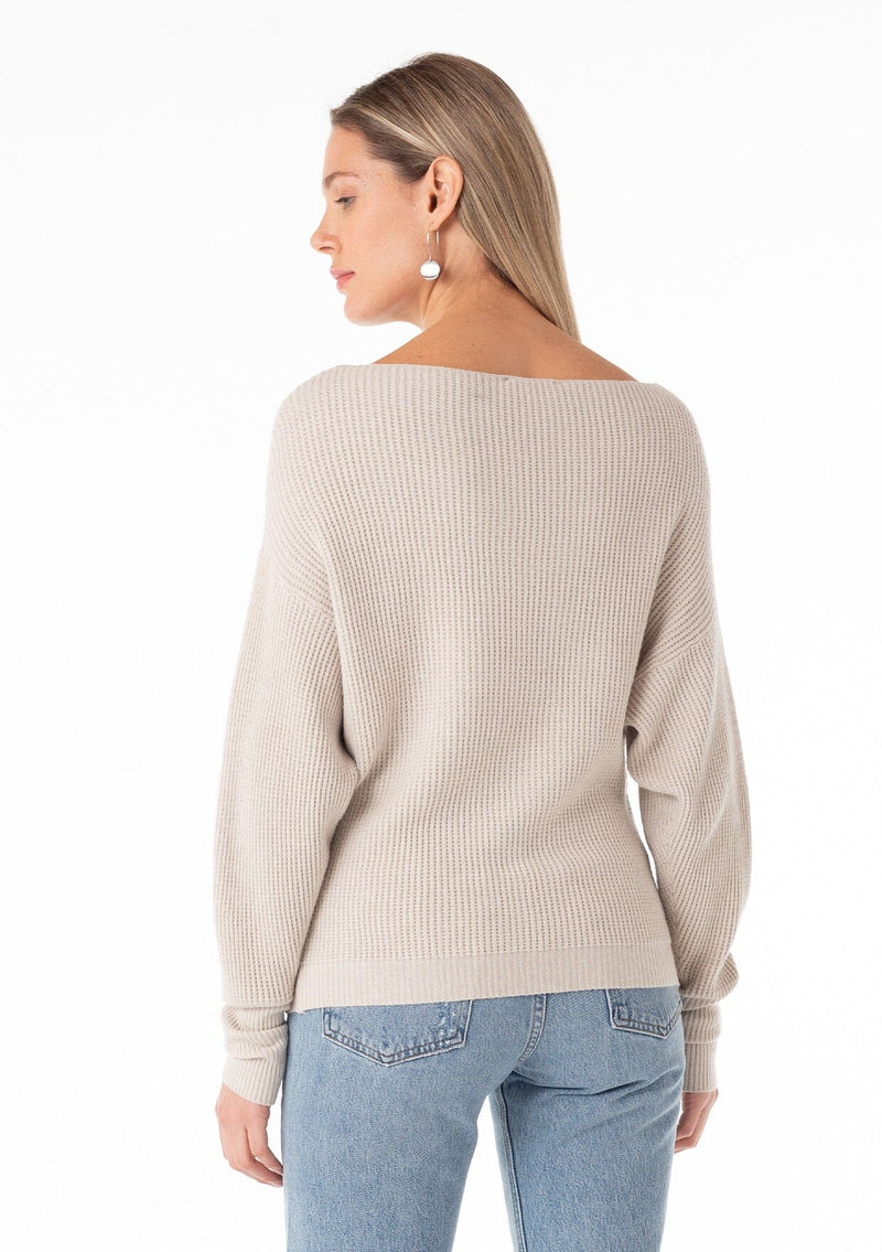 [Color: Heather Stone] A back facing image of a blonde model wearing an off white, stone grey waffle knit pullover sweater. With long sleeves, a relaxed fit, and a wide neckline that can be worn off the shoulder. 
