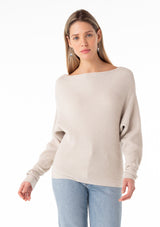 [Color: Heather Stone] A half body front facing image of a blonde model wearing an off white, stone grey waffle knit pullover sweater. With long sleeves, a relaxed fit, and a wide neckline that can be worn off the shoulder. 