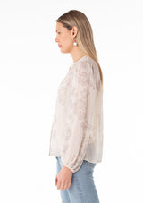 [Color: Natural/Taupe] A side facing image of a blonde model wearing a sheer chiffon bohemian spring blouse in a natural and taupe mixed floral print. With a button front, a v neckline, long sleeves, and a relaxed fit. 