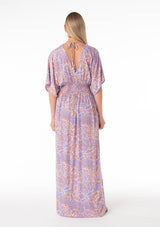 [Color: Ivory/Coral] A back facing image of a blonde model wearing a best selling resort bohemian maxi dress in a purple and coral pink retro floral print. With short kimono sleeves, a surplice v neckline, a smocked elastic waist, and an open back with tie closure. 