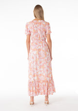 [Color: Peach/Light Pink] A back facing image of a blonde model wearing a classic spring bohemian maxi dress in a peach pink floral print. With short puff sleeves, a front slit, an elastic waist, and a drawstring v neckline with adjustable tie. 